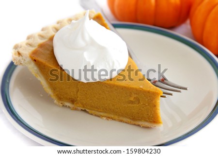 Pumpkin custard pie slice with whipped cream topping.