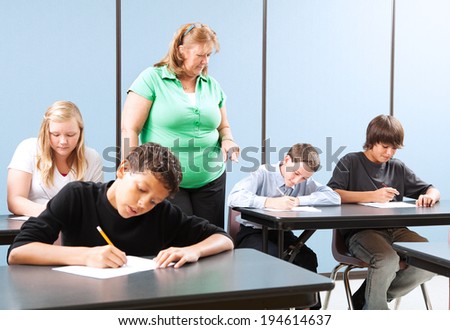 Teacher supervising high school students as they take and achievement test.