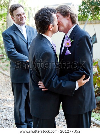 Two grooms kiss eachother in front of the minister at their gay marriage ceremony.