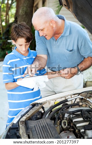 Father teaching his son how to check the oil on the family car.