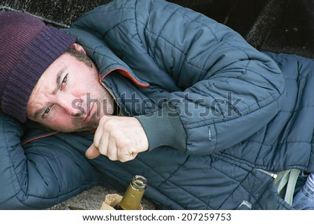 Homeless man sleeping on the ground in the cold with a cough.