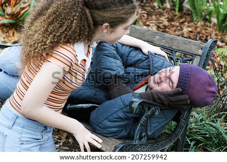 Teen girl volunteers to help homeless man in the park.  Or daughter helping father.