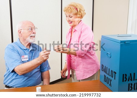 Volunteer gives an I Voted sticker to an elderly female voter.