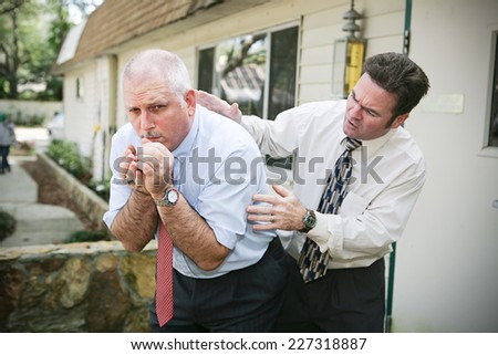 Mature businessman with a bad cough.  His friend and colleague is worried about him and pats him on the back trying to help.  Vignette added.