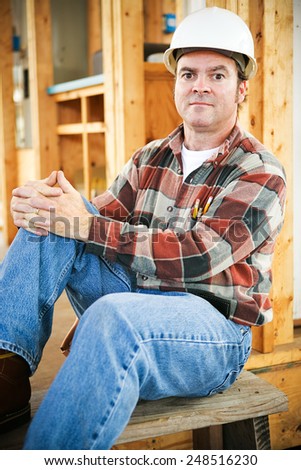 Handsome construction worker sitting down for a rest, with a serious expression.