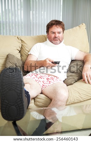 Injured man at home on the couch, wearing a foot brace and neck collar.