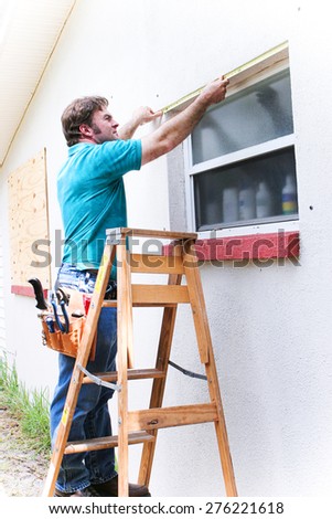 Contractor measuring window to cover with hurrican shutters.