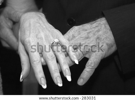  married mature couple holding hands and displaying their wedding rings