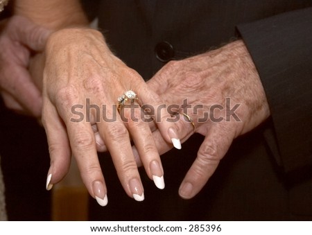 The hands of a mature, newly married couple showing off their rings (color).