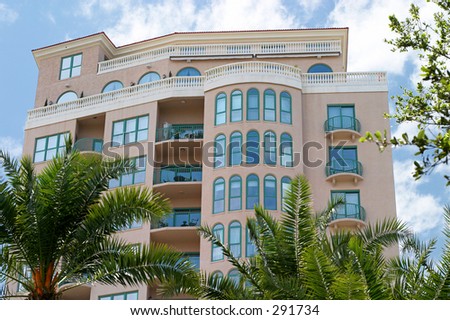 A tropical, art deco style condo with a bright blue sky and palm trees.