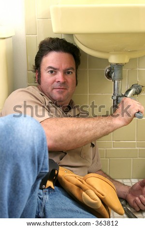 A plumber under a sink, fixing a clog.