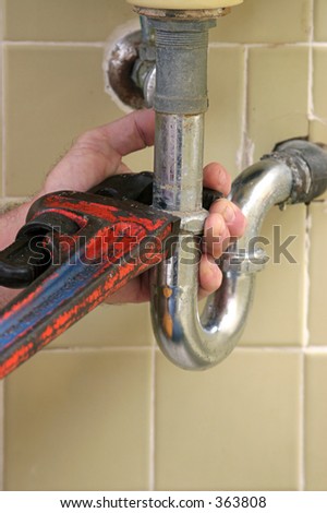 A plumber\'s wrench repairing a leaky pipe.