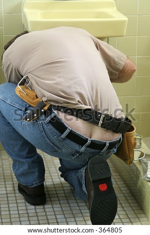 A plumber fixing a sink - exposing butt crack.