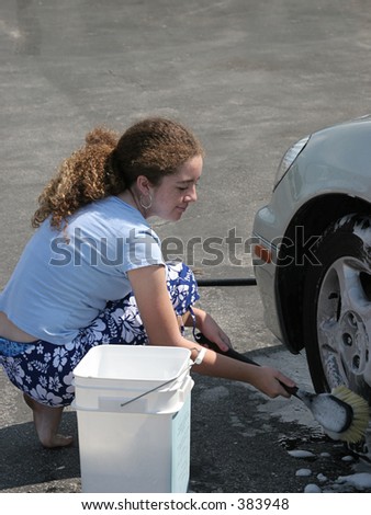 A teenaged girl washing a car tire.