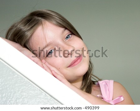 A little girl resting her head on her hands looking sleepy - diagonal