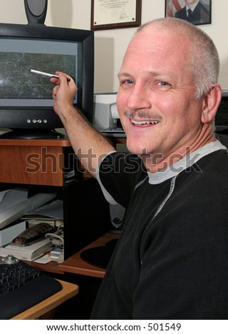 A meteorologist (weather man) pointing to his computer and smiling.  He has good news about the weather.