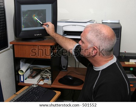 A meteorologist tracking a hurricane on his computer and pointing out the eye. (focal point is his head/face)