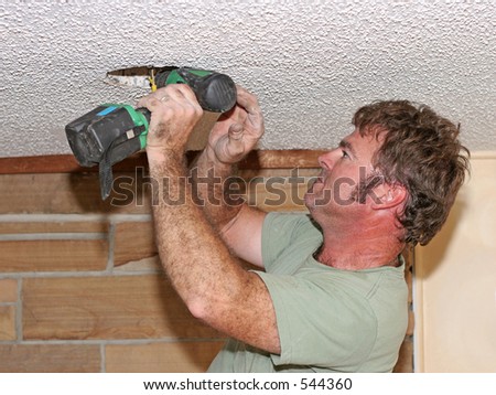 an electrician drilling out a fixture - hot sweaty work
