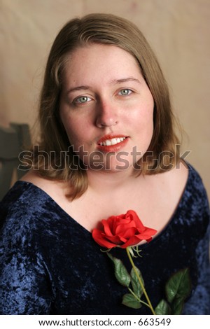 A beautiful high school senior posing for her senior portrait, with a red rose.