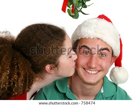 A teen girl kissing a very surprised boy under the mistletoe.