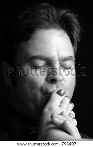 A handsome man kissing a woman\'s toes. Black and White