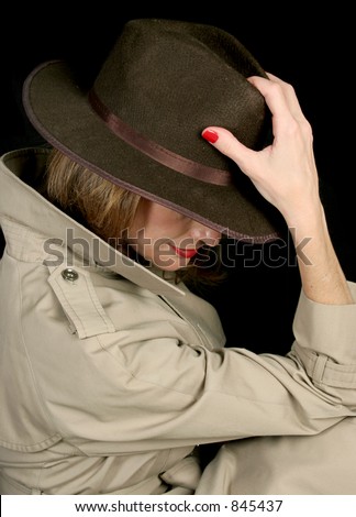 A beautiful, mysterious woman in a trench-coat and fedora hat, turned away so her face is hidden.