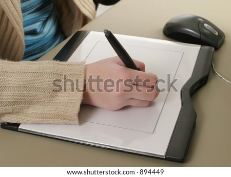 A closeup of one hand drawing on a computer graphics tablet.