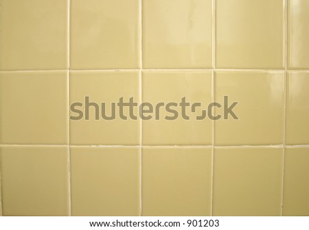 A background of greenish yellow bathroom tile.  Grout needs repair.