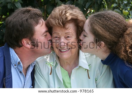 A sweet grandmother receiving kisses from her family.