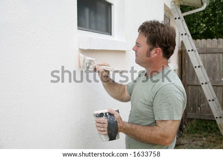 A house painter edging around a window with a brush.  Room for text.