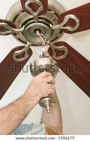An electrician wiring up a ceiling fan.  All work is being performed to code by a licensed master electrician.