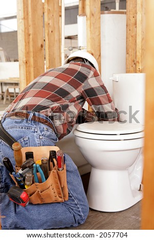 A plumber installing fixtures in new construction.  Focus on his tool pouch.