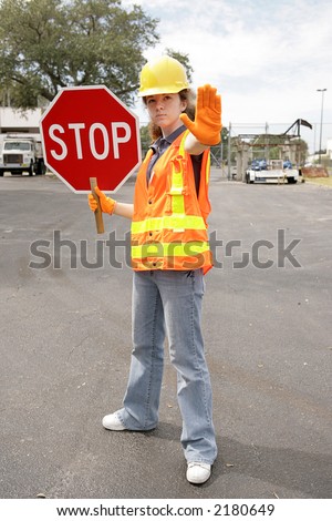 A female construction worker holding a stop sign.  Full body view.