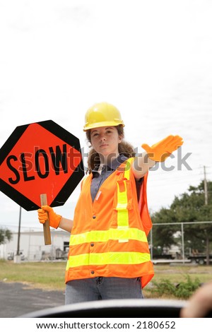A road crew member holding a sign & telling a driver to slow down. Room for text