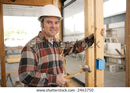 An electrician on a construction site installing an electrical box.  Model is a licensed master electrician.  Work depicted is accurate and in compliance with codes and safety standards.