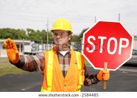 A construction worker holding a stop sign and directing traffic.