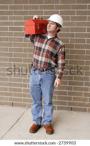 A complete, full-length view of a working man with his hard hat and toolbox.