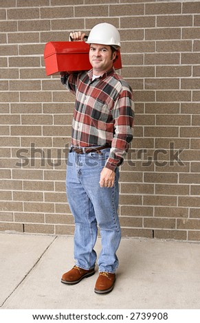 A full body view of a handsome blue collar worker with his toolbox and hardhat.