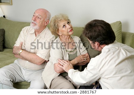 A senior couple in marriage counseling.  They have their backs turned and are ignoring each other while the therapist tries to reconcile them.