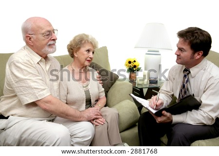 A senior couple speaking with a marriage counselor.  Could also be a salesman in their home.  Isolated on white with focus on couple.