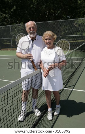 An attractive senior couple on the tennis courts.  Full view vertical.