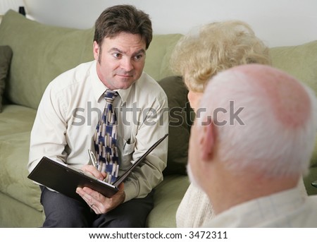 A counselor with a caring expression sitting across from an elderly couple.