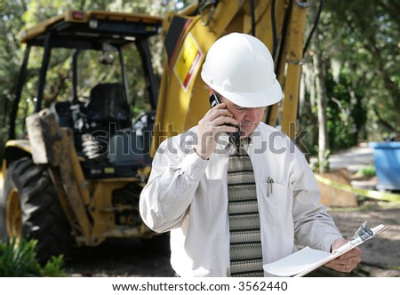 An engineer on a construction site discussing plans over the phone.