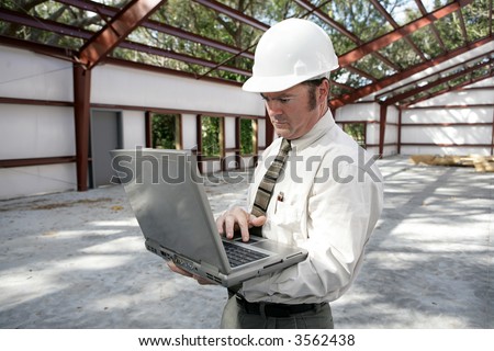 A construction inspector or engineer filling out his report on his laptop.