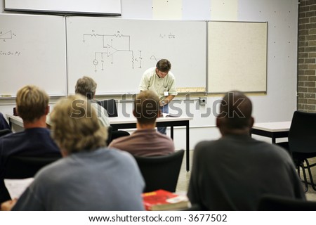 An adult education class in electricity.  Focus on the electrical circuit diagram on the board.