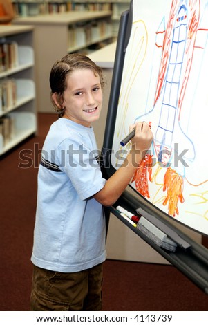 A cute school boy drawing a picture in class.