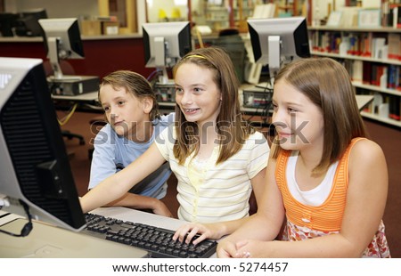A group of school children having fun working on a computer in the school media center.