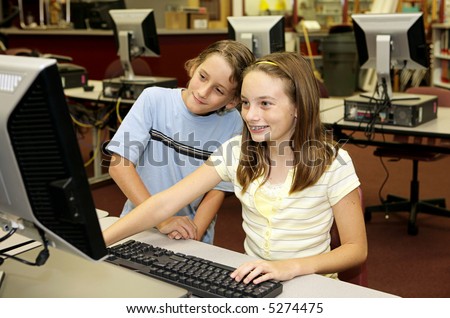 Two school children doing research together on the library computers.