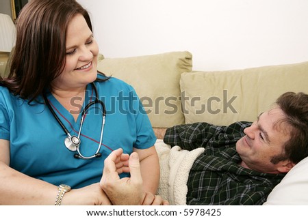 Kind, friendly home health nurse taking her patient\'s pulse.  Both are smiling.
