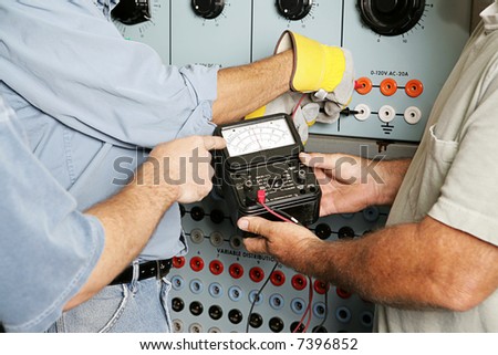 Team of actual electricians testing the voltage on an industrial power distribution center. All work is being performed according to industry code and safety standards.